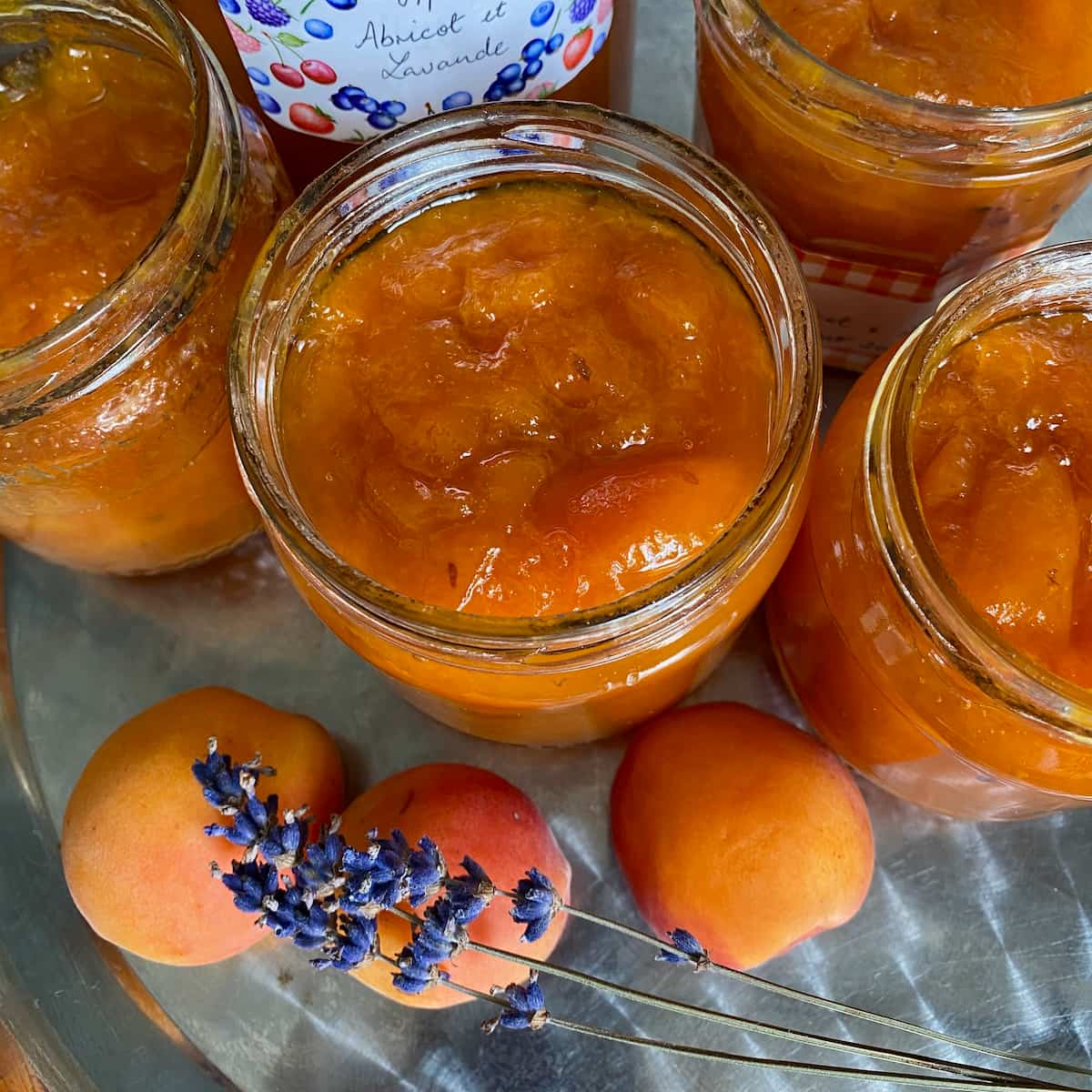 Apricot-lavender-jam glass jars filled with bright orange apricot jam with sprigs of purple lavender