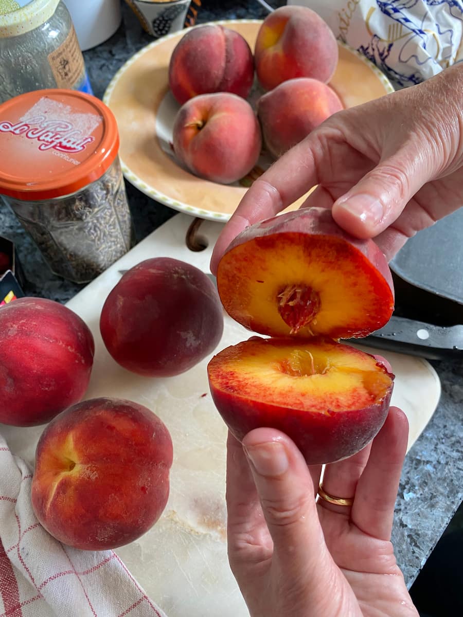 twisting open a halved peach to remove the stone or pit